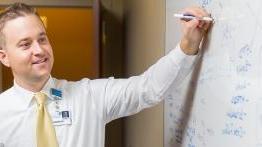 校友 Patrick Halinsky uses a white board to map a process at a local hospital.