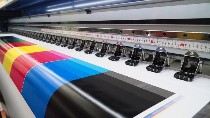 Up close image of the inside of a printer with bright colored ink and white glossy paper