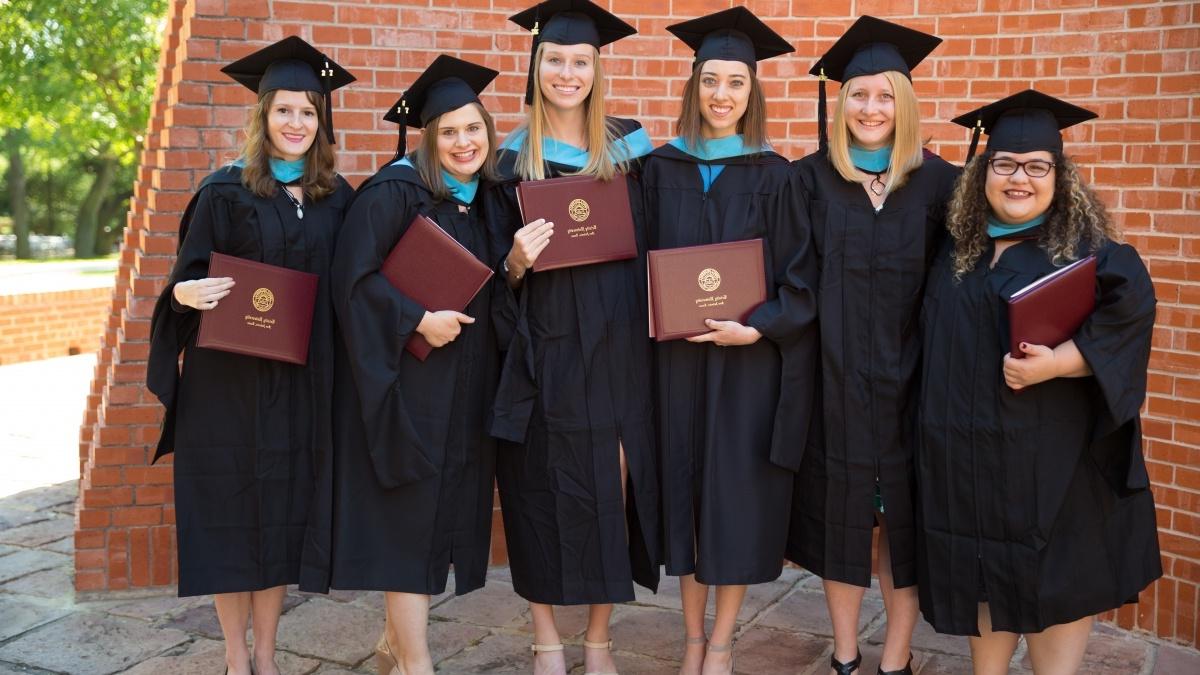 毕业的学生们戴着帽子，穿着长袍，拿着毕业证书